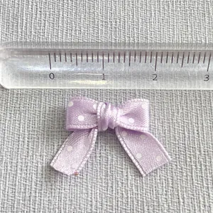 Macro shot of 2cm light purple satin bow with white dots and ruler for scale