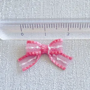 Detailed view of pink striped ribbon bow with ruler showing 2cm size for DIY crafts