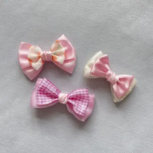 Detailed close-up of three pink and white plaid mesh bowknot DIY hair accessories