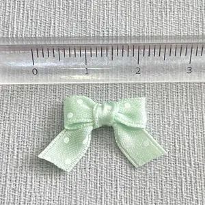 Detail of 2.2cm mint green polka dot bow accessory measured with a clear ruler scale