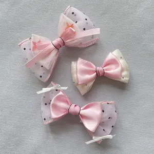 Detailed view of handmade pink plaid mesh bows with lace edges and rhinestone accents