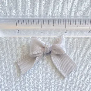 Close-up of 2cm mini macaron ribbon bow showing precise measurement on a ruler