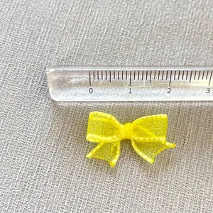 Detailed close-up of a 3cm mini yellow mesh bow with white stitching for DIY hair crafts