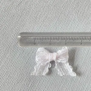 Vue détaillée d'un petit nœud en organza blanc de 2cm avec bords en dentelle fine