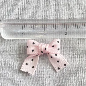 Detailed close-up of a 2.5cm pink polka dot ribbon bow with measurement scale