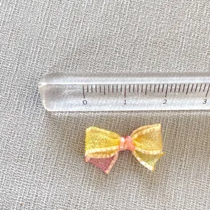 Detailed size view of 2.5cm mini pink and yellow organza bow with golden edges