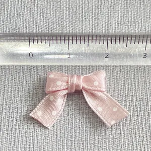 Macro detail of a 2.5cm pink polka dot ribbon bow accessory with white printed dots