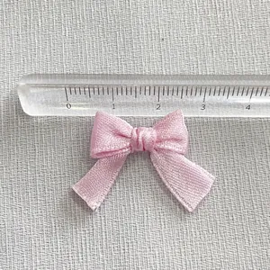 Detail showing a 2.8cm handmade pink satin ribbon bow accessory for DIY craft hair clips