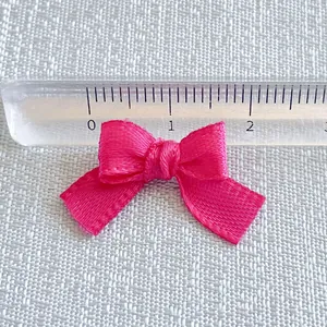 Detail shot of 20mm rose pink satin ribbon bow showing size measurement with a ruler