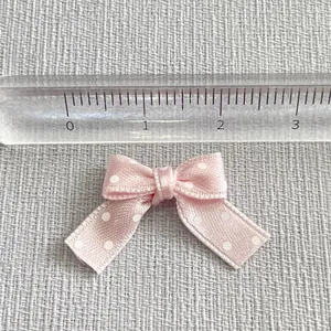 Macro shot of small pink satin ribbon bow with white polka dots for DIY decoration