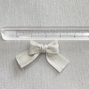 Detail view of a handmade silver ribbon bow accessory with ruler showing 4cm width