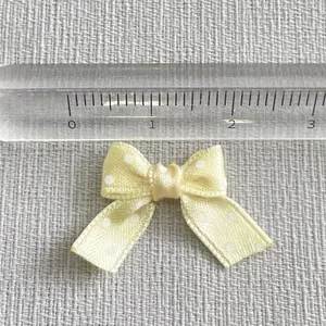 Close-up of 2cm mini yellow polka dot ribbon bow with a ruler showing exact size