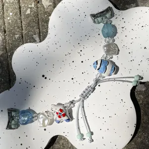 Detail of beaded watch band with ceramic fish charm and adjustable woven strap