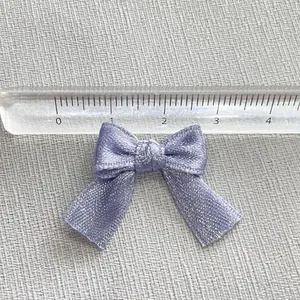 Close-up of a 2.5cm lavender glitter ribbon bow with a ruler showing the exact size