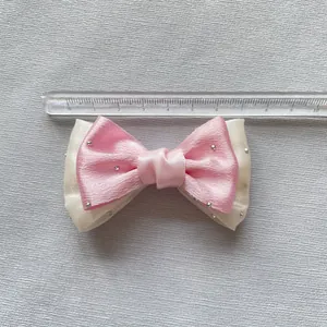Detail shot of a pink ribbon bow accessory with silver rhinestones measuring 8cm wide