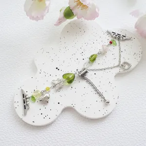 Green beaded Apple Watch band with butterfly charms and heart pendants on a tray