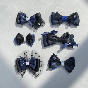 Dettaglio di fiocchi per capelli blu scuro e neri con perle, strass e bordi in pizzo