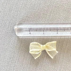 Detailed close-up of 3cm mini beige mesh bow showing texture and ruler for size