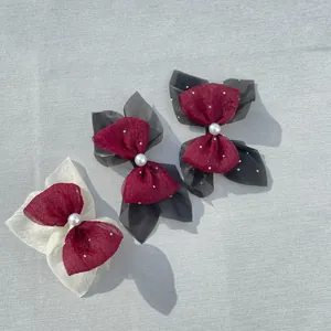 Close-up of three-piece red tulle bows with scattered pearls and central large pearl decor