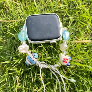 Handmade light blue beaded watch strap with ceramic cat element and adjustable woven cord