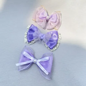 Detailed set of purple bow hair clips featuring lace, ribbon, and pearl center accents