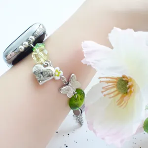 Detail of beaded Apple Watch band with green glass beads, heart charm and butterfly charm