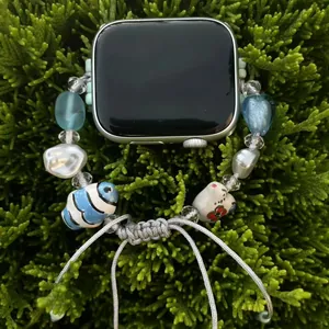 Handmade beaded watch band with ceramic bunny and heart elements in fresh blue on green plants