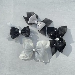 Detailed view of handmade bow accessories with translucent organza and white faux pearl