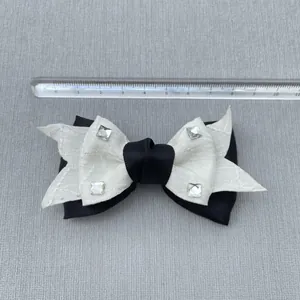 Detail of 10.5cm black and white cotton bow accessory with lace and small square rhinestones