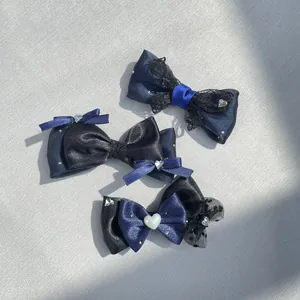 Dettaglio di fiocchi per capelli blu e neri con pizzo, raso e fibbie a cuore
