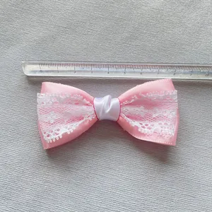 Detailed view of an 8.5cm pink satin and white lace bow accessory with a measuring ruler
