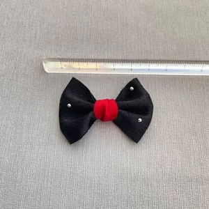 Detail view of a 6cm black satin bow with red center and silver studs for DIY crafts