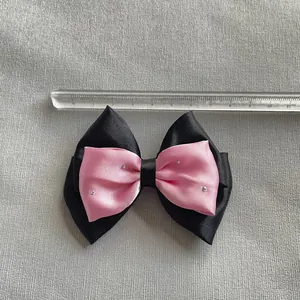 Detalle de un lazo negro y rosa con diamantes de imitación, ancho de unos 8,5 cm