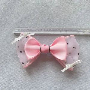 Pink silk bow with black polka dot mesh showing 11.5cm width measurement with a ruler