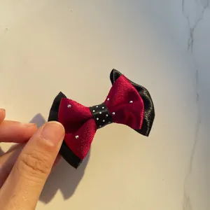 Close-up of handmade red and black ribbon bow with white pearls and polka dot center