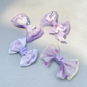 Detailed view of handmade purple bow hairpins with satin ribbon and crystal rhinestones