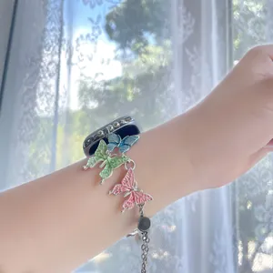 Close-up of pearl charm iWatch strap with blue, green, and pink butterfly pendants