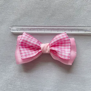 Detailed view of a pink plaid mesh bow accessory with silver beads and size measurement