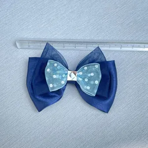 Detalle de un lazo azul de capas de 10cm con diamantes de imitación y regla de medida