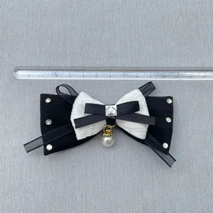 Detail of DIY bow accessory featuring black white ribbons and pearl drop on ruler