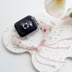 Close-up of pink crystal beads and silver butterfly charms on an adjustable watch band