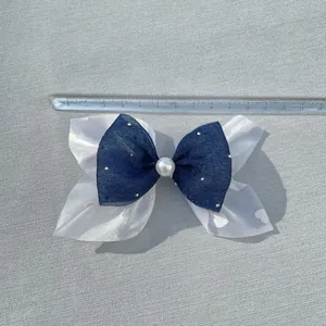 Double-layer navy and organza bow with pearls and rhinestones shown on a measuring scale