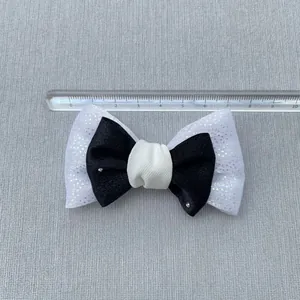 Close-up of black and white bow accessory with silver rhinestones and 8cm measurement scale