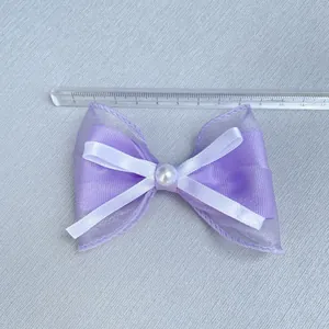 Detail of purple organza bow with white pearl accent and silk layer, 8.5cm wide accessory