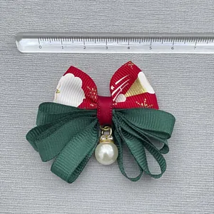 Handmade Christmas bow accessory in red and green ribbon with a pearl pendant