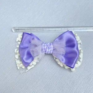 Detail of 11cm purple bow accessory with satin mesh lace and pearl beads on ruler