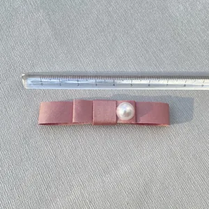 Pink satin bow hair clip with white pearl detail and ruler showing 7.5cm size