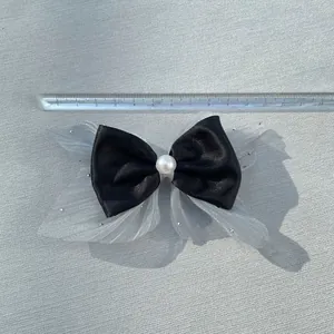Detailed top view of a 12cm black satin bow with mesh wings and faux pearl accent