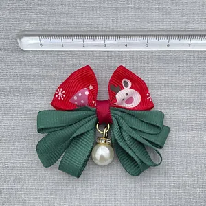 Detail of a Christmas bow with reindeer print, green ribbons and a pearl pendant
