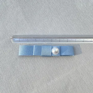 8.3cm light blue grosgrain ribbon bow hair clip with central white pearl on gray fabric